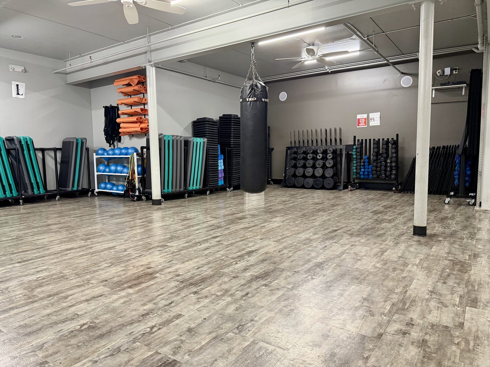 Group fitness studio with heavy bag, step platforms, mats and dumbbells