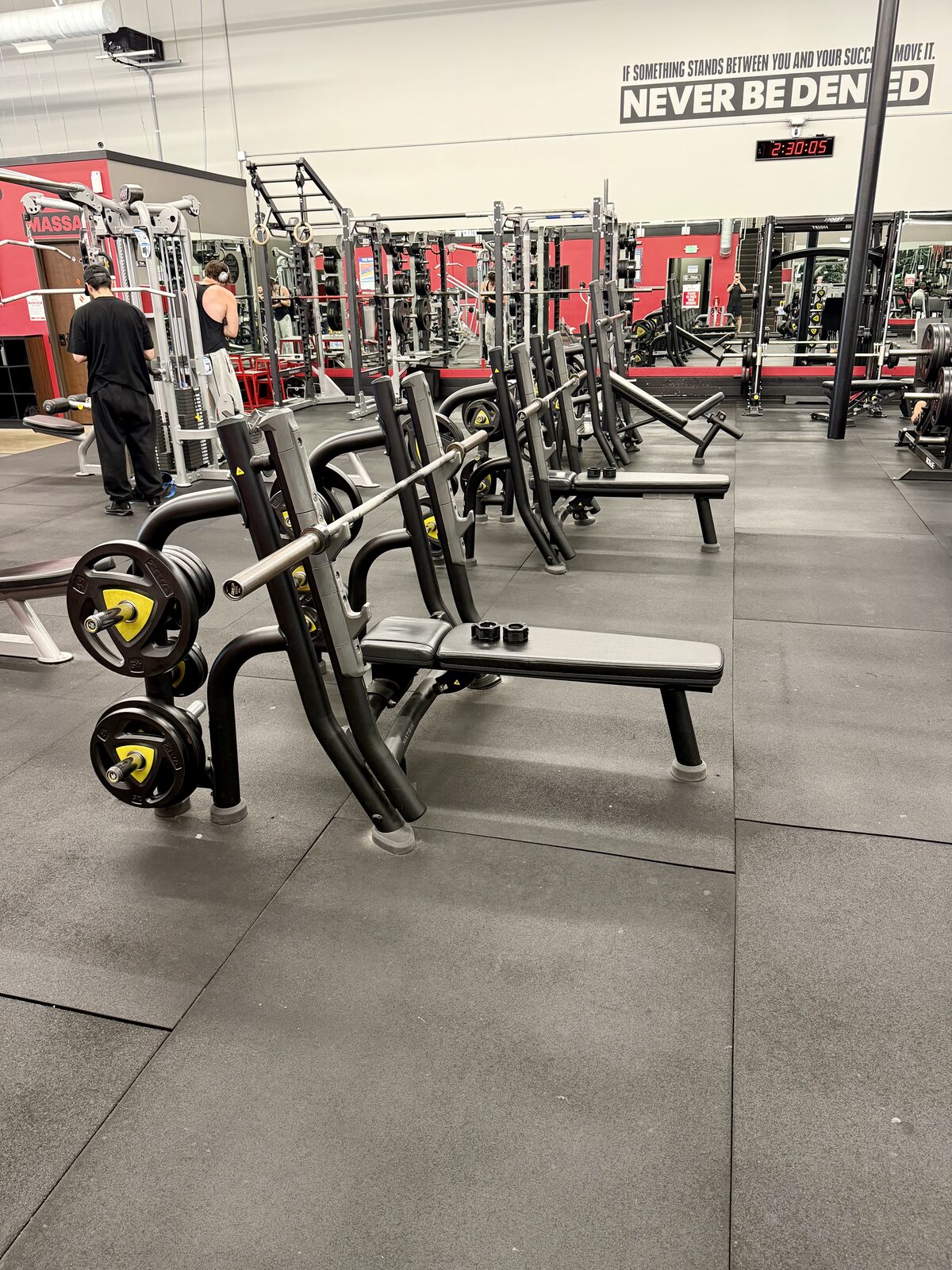 Row of Olympic bench press stations loaded with plates